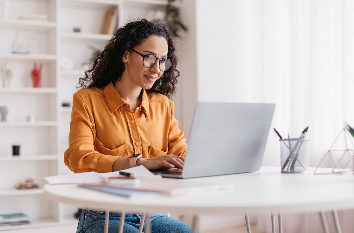 A women using a laptop looking interested by what is on the screen.