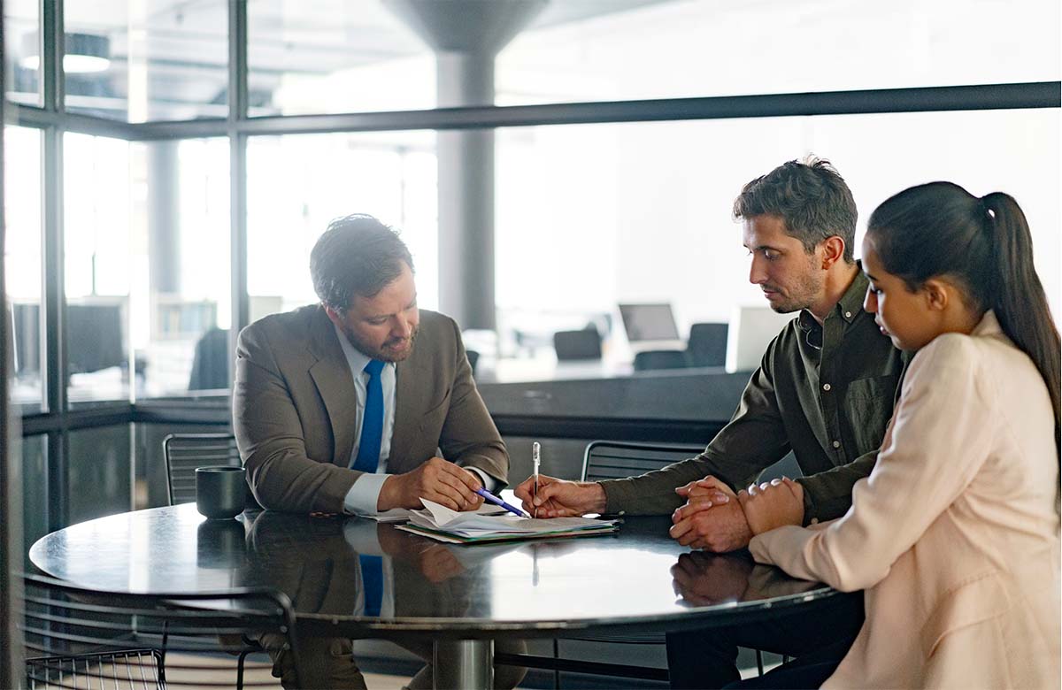 Decorative image: A woman and a man talking with a financial advisor about their finances. 