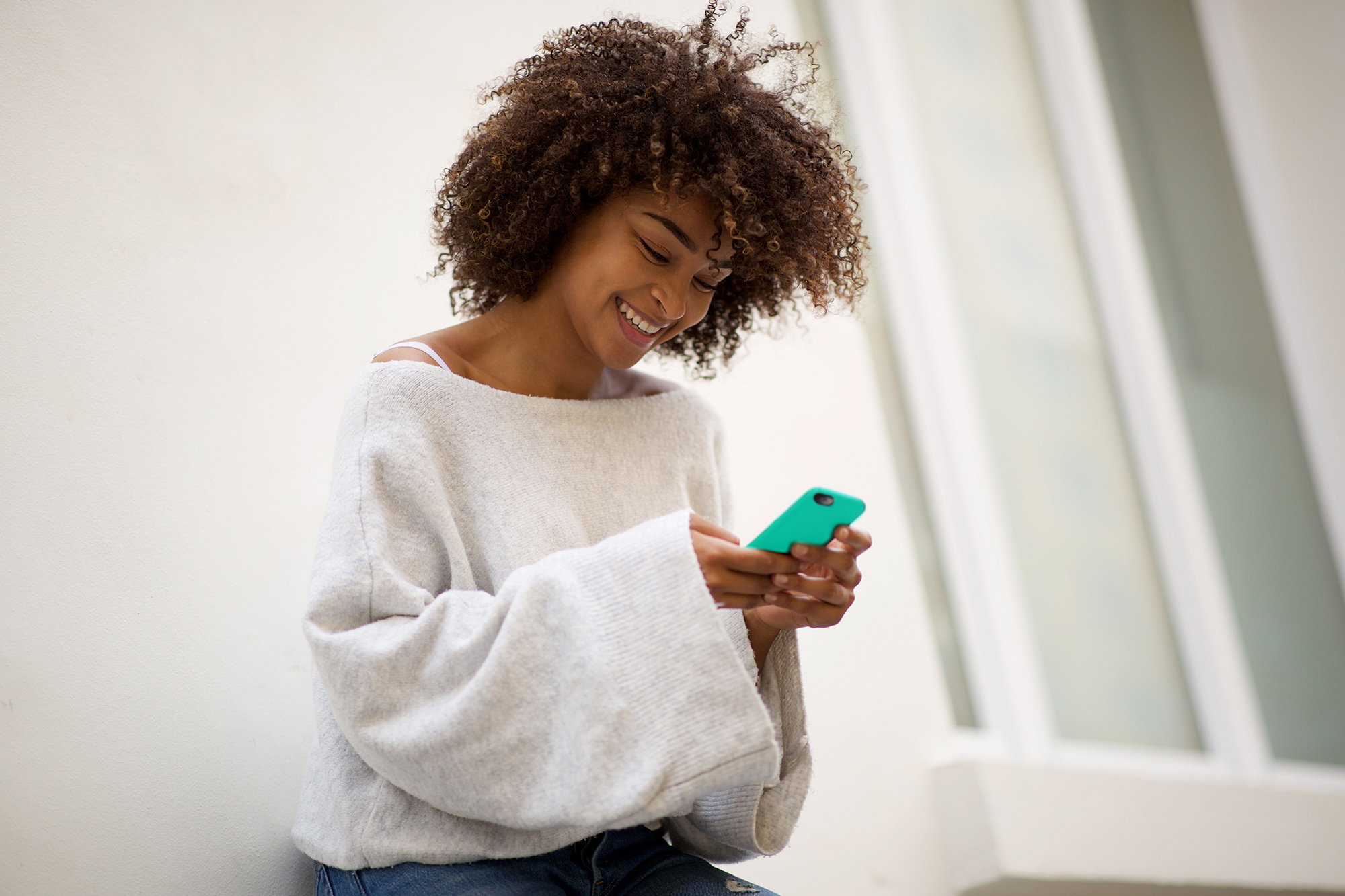 Jeune femme qui sourit en regardant l'cran d'un tlphone intelligent.